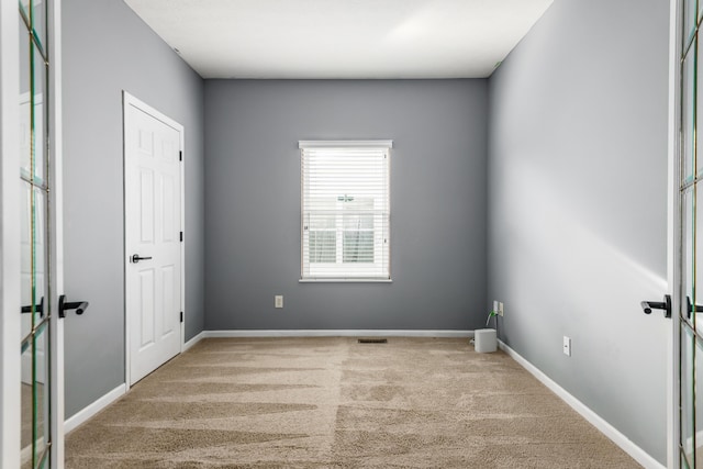 carpeted spare room with visible vents and baseboards