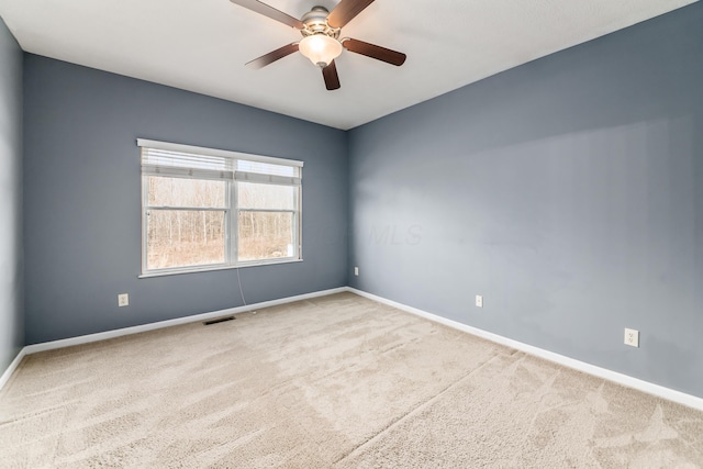 unfurnished room with carpet floors, visible vents, baseboards, and a ceiling fan