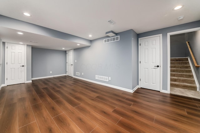 finished basement with baseboards, stairs, visible vents, and dark wood finished floors