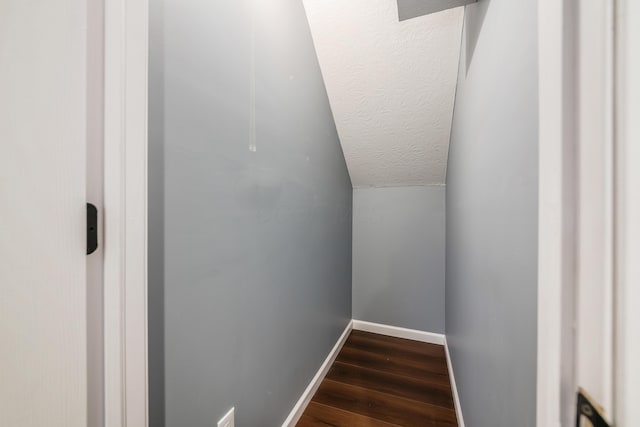 stairs with lofted ceiling, a textured ceiling, wood finished floors, and baseboards