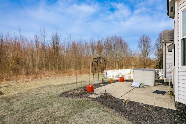 view of yard with a storage shed, fence, an outdoor structure, and a patio