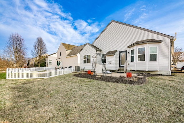 rear view of property featuring entry steps, central air condition unit, fence, and a yard