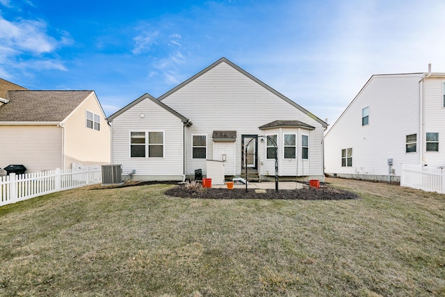 rear view of house with fence private yard, a lawn, and central AC