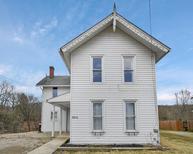 back of property with a chimney and fence