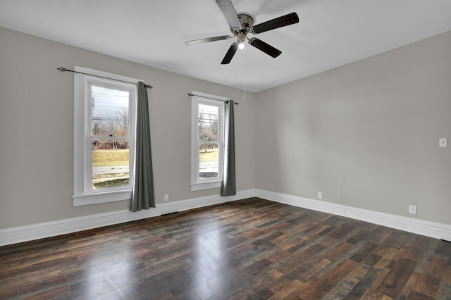 unfurnished room with dark wood-style flooring, a ceiling fan, and baseboards