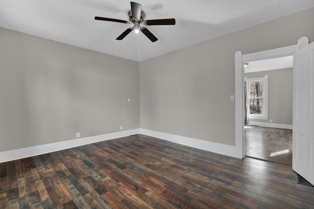 empty room featuring dark wood-style flooring, a ceiling fan, and baseboards