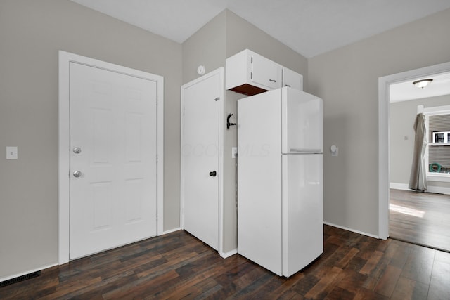 kitchen featuring baseboards, dark wood-style flooring, freestanding refrigerator, and white cabinets