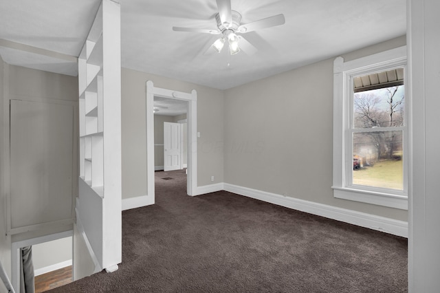 interior space with ceiling fan, baseboards, and dark colored carpet