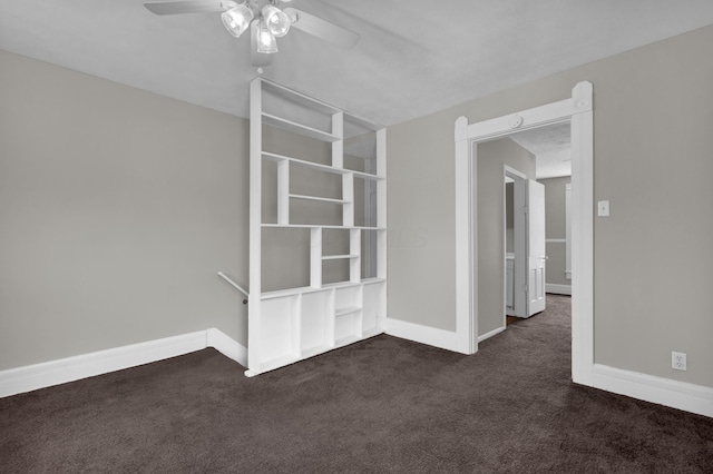 spare room featuring dark carpet, a ceiling fan, and baseboards