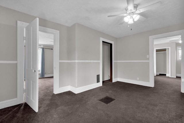 unfurnished room featuring visible vents, baseboards, ceiling fan, dark colored carpet, and a textured ceiling