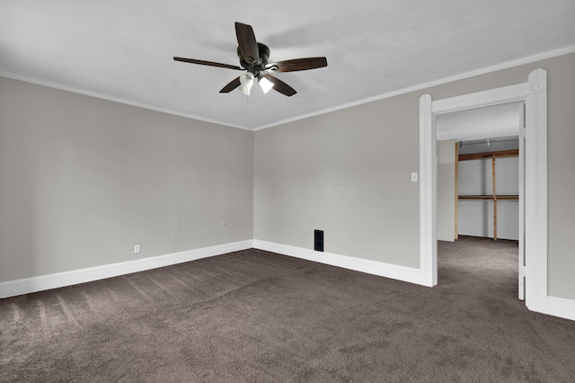 spare room with ornamental molding, dark colored carpet, baseboards, and a ceiling fan