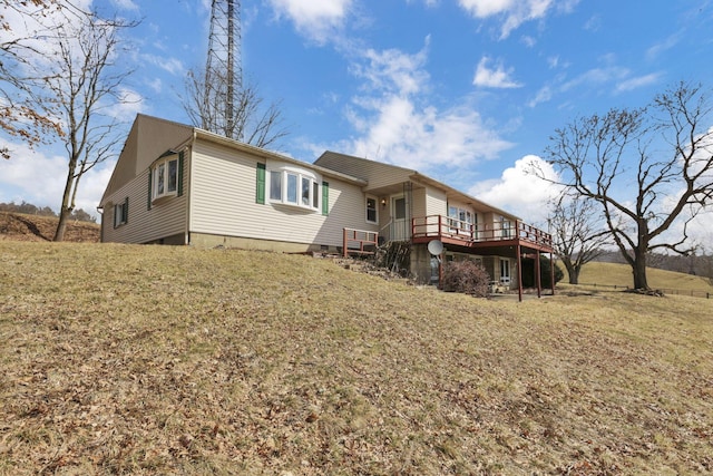 back of property with a deck and a lawn