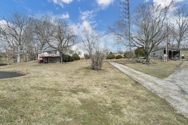 view of yard featuring dirt driveway and a deck