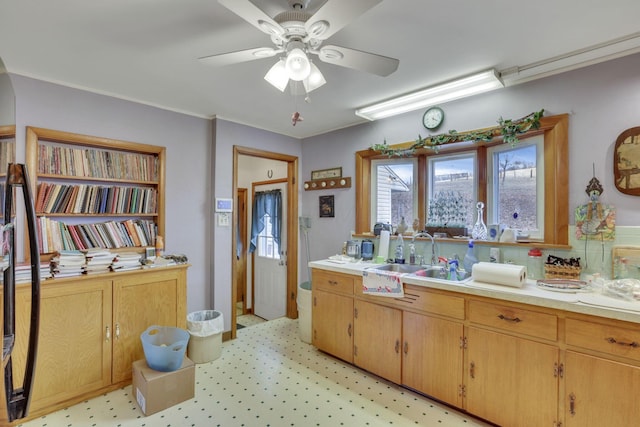 kitchen featuring light floors, a ceiling fan, light countertops, and a sink