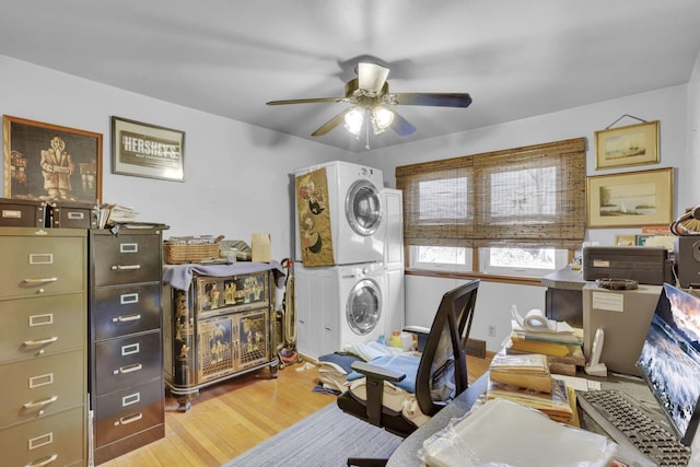 office space featuring ceiling fan, light wood-type flooring, and stacked washing maching and dryer