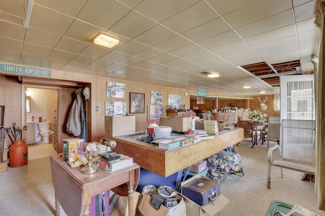 misc room featuring a drop ceiling and wooden walls