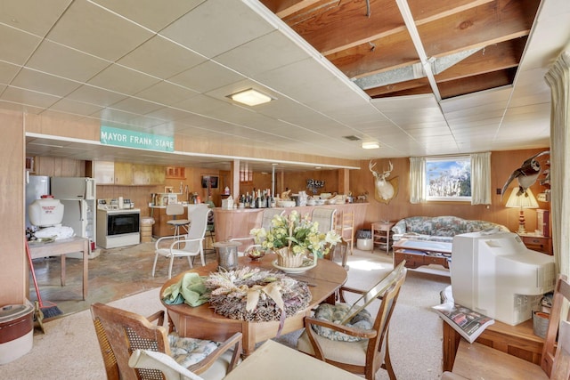 dining room featuring visible vents, a drop ceiling, and wooden walls