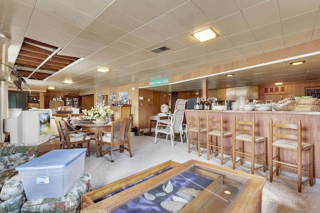 carpeted dining room featuring a bar and visible vents