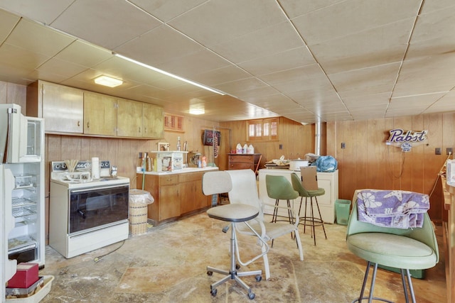 kitchen with a paneled ceiling, washer / clothes dryer, light countertops, wood walls, and white appliances