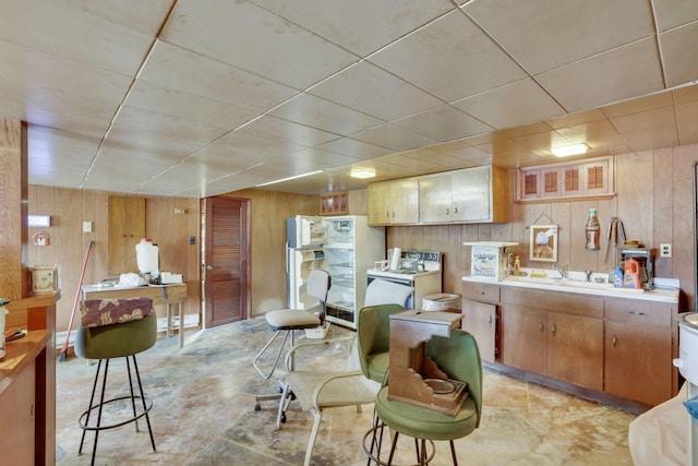 kitchen featuring light countertops, a sink, washer / dryer, and wooden walls