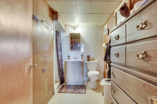 bathroom featuring tile walls, a shower with shower curtain, vanity, and toilet