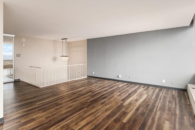 unfurnished room with dark wood-style floors and baseboards