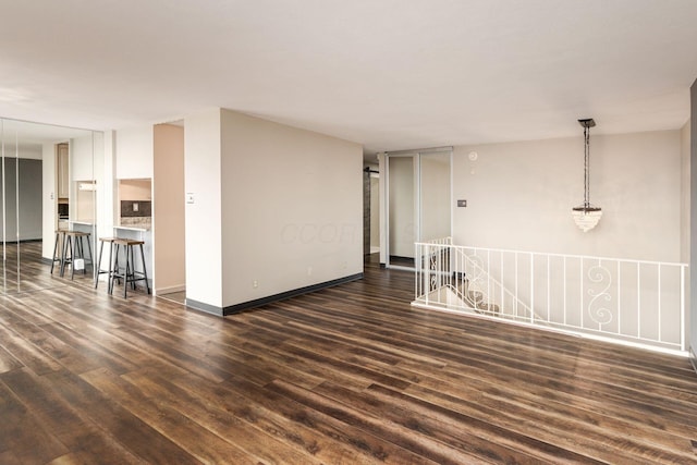 spare room with dark wood-type flooring and baseboards