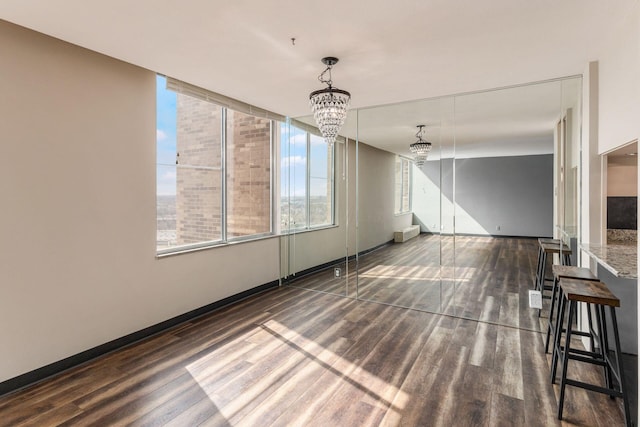 interior space featuring a notable chandelier, wood finished floors, and baseboards