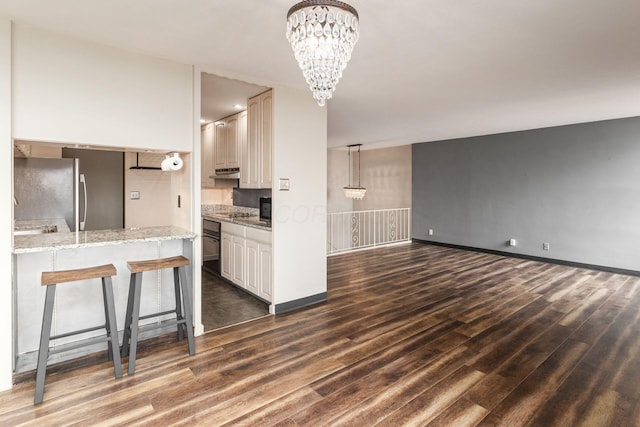 kitchen featuring a chandelier, dark wood-type flooring, under cabinet range hood, and black appliances