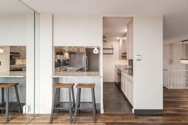 kitchen with freestanding refrigerator, dark wood finished floors, a sink, and a breakfast bar area