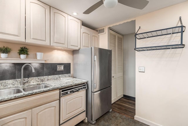 kitchen with visible vents, paneled dishwasher, freestanding refrigerator, a sink, and light stone countertops