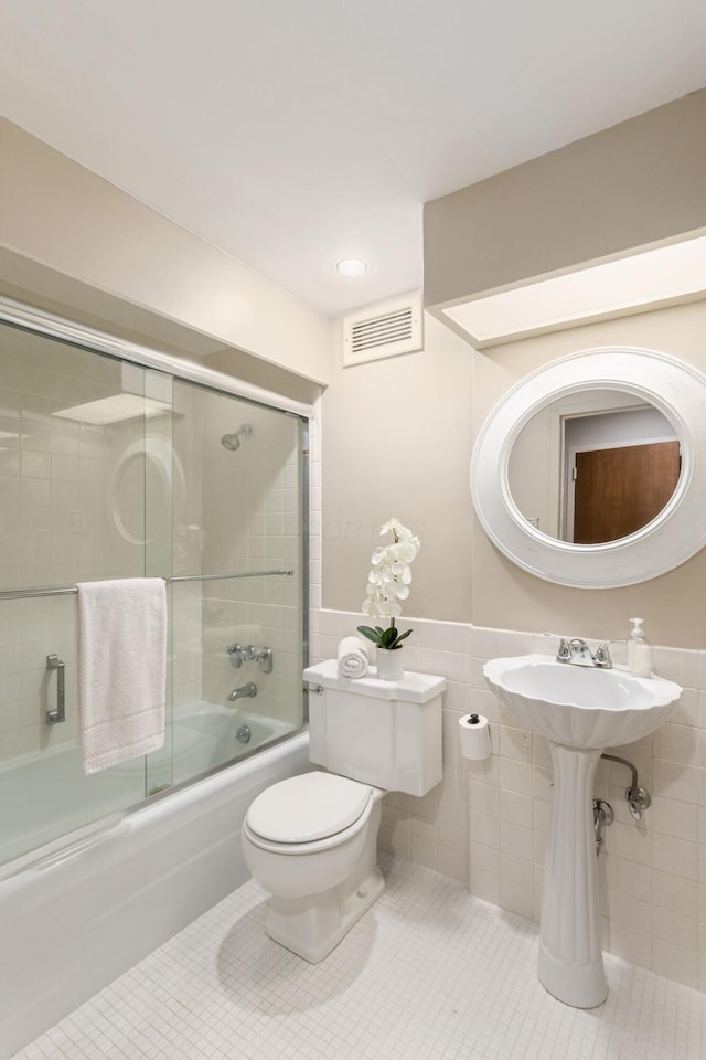 full bath with toilet, shower / bath combination with glass door, tile walls, visible vents, and tile patterned floors