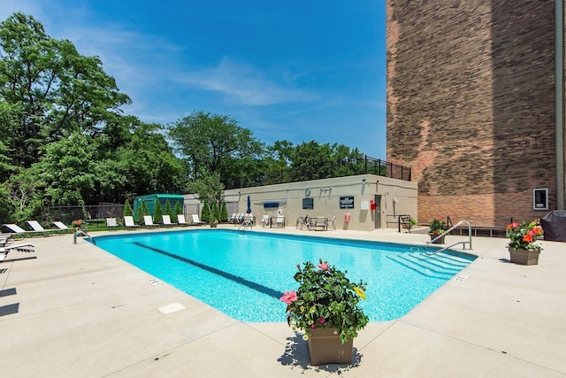 pool with a patio area and fence