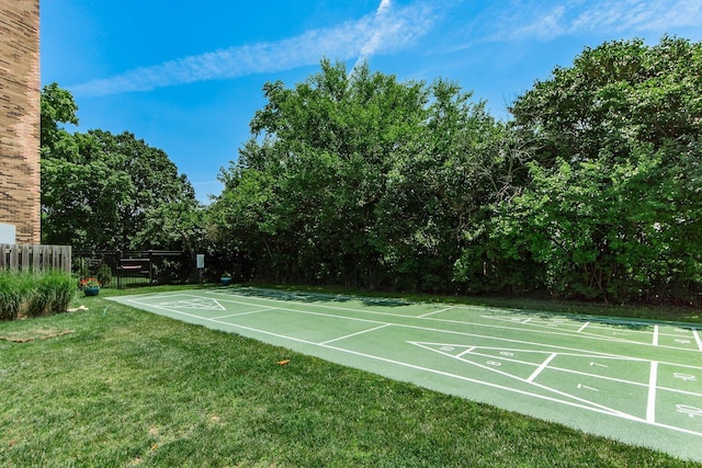 surrounding community featuring shuffleboard, a lawn, and fence