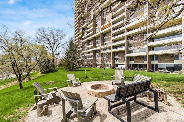 view of property's community featuring a yard, an outdoor fire pit, and a patio