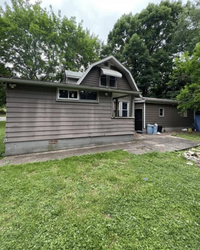 rear view of house with a lawn, a gambrel roof, and a patio