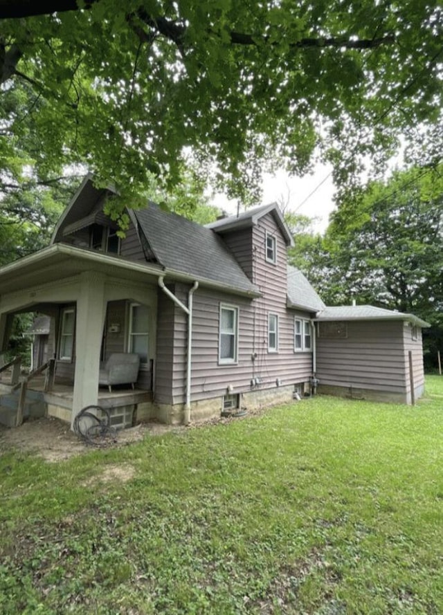 rear view of house with a shingled roof, a lawn, and a porch