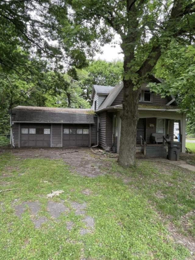 view of yard with a garage, covered porch, and driveway