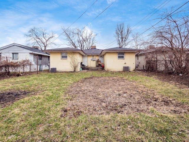 rear view of house featuring fence, central AC unit, a lawn, and stucco siding