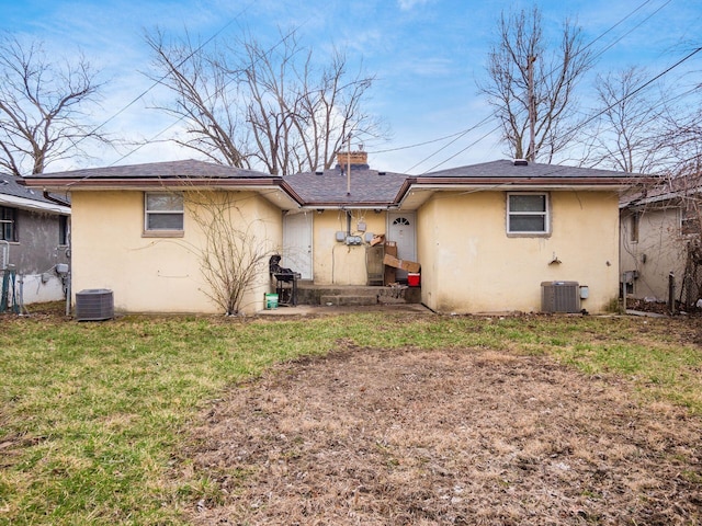 back of property with stucco siding, a yard, and central AC unit