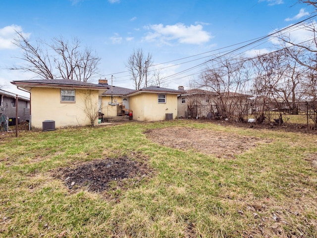 rear view of house featuring central air condition unit, a lawn, fence, and stucco siding