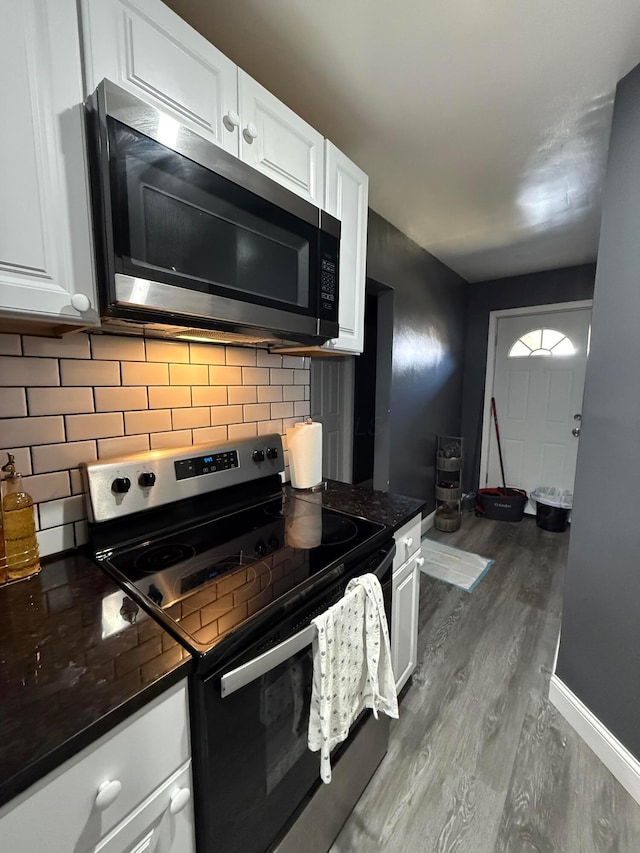 kitchen with appliances with stainless steel finishes, dark countertops, decorative backsplash, and white cabinets