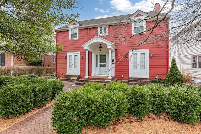 colonial inspired home featuring entry steps, french doors, and a chimney