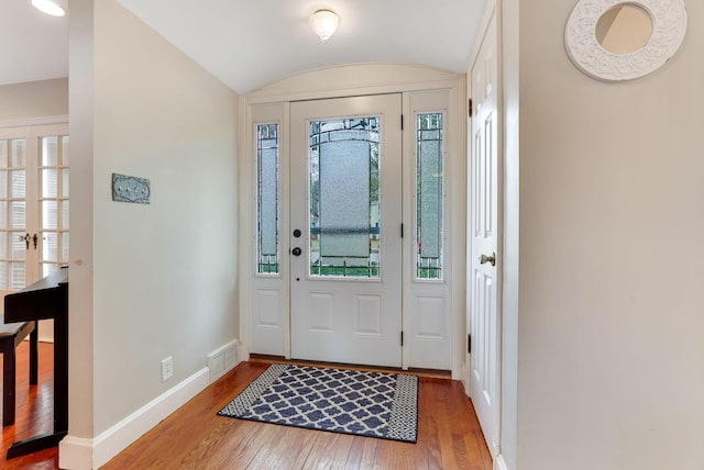 foyer with lofted ceiling, visible vents, baseboards, and hardwood / wood-style flooring