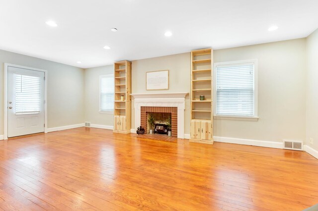 unfurnished living room featuring a wealth of natural light, a fireplace, and light wood-style flooring