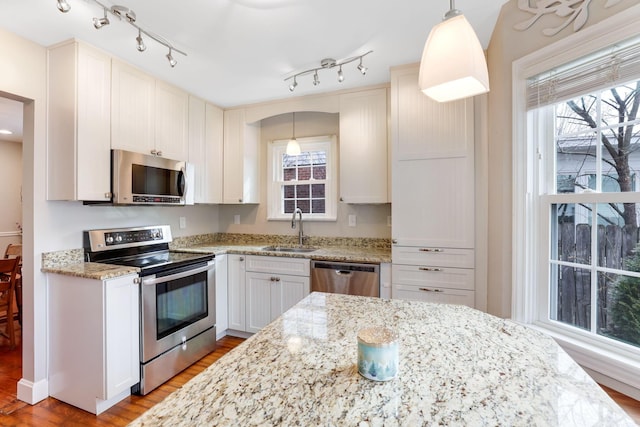 kitchen with a healthy amount of sunlight, appliances with stainless steel finishes, light stone counters, and a sink