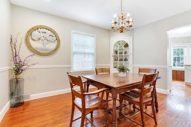 dining room featuring light wood-type flooring, visible vents, baseboards, and a chandelier