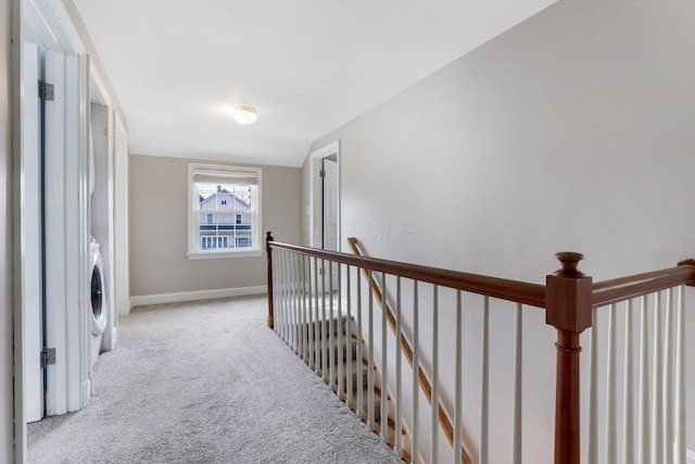 hall with carpet floors, baseboards, and an upstairs landing