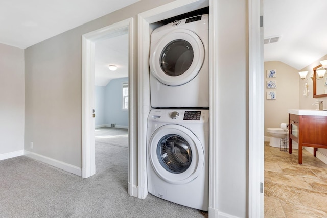 laundry room with stacked washer and clothes dryer, visible vents, light carpet, laundry area, and baseboards