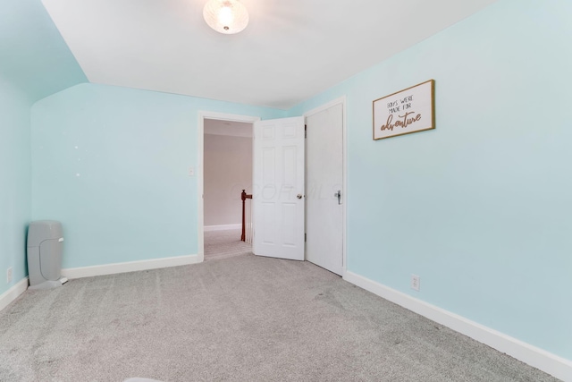 unfurnished bedroom featuring lofted ceiling, carpet flooring, and baseboards